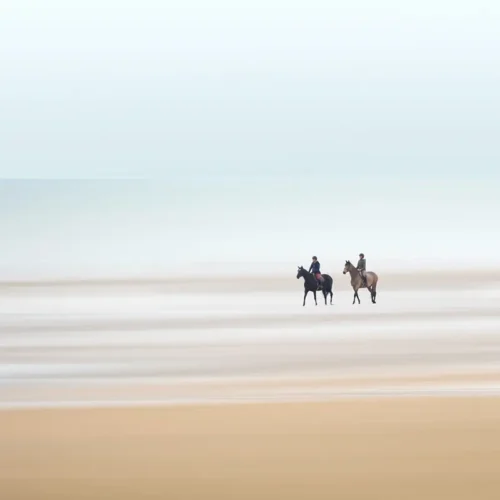 Dos jinetes en una playa tranquila, en una composición artística