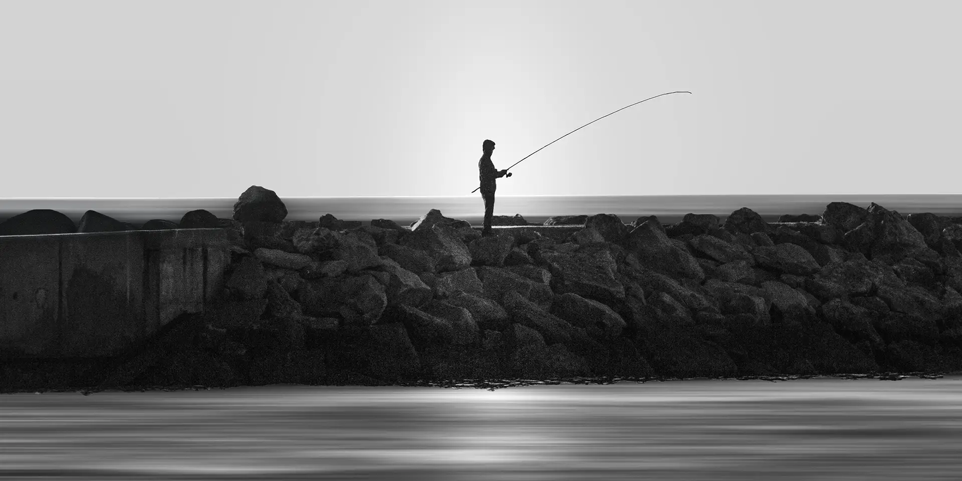 photographie noir et blanc – pêcheur sur digue