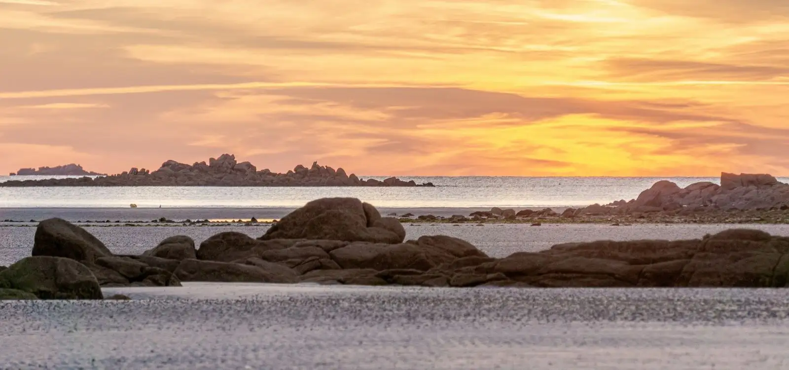 Photographie artistique de Bretagne au coucher de soleil sur une plage de rochers